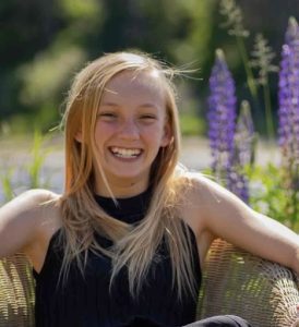 Compass scholar smiles in field of purple flowers